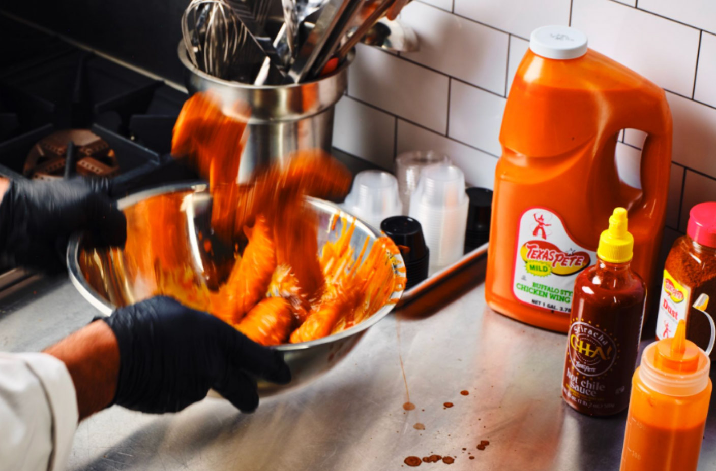 Tossing chicken wings in Texas Pete Mild Buffalo Wing Sauce